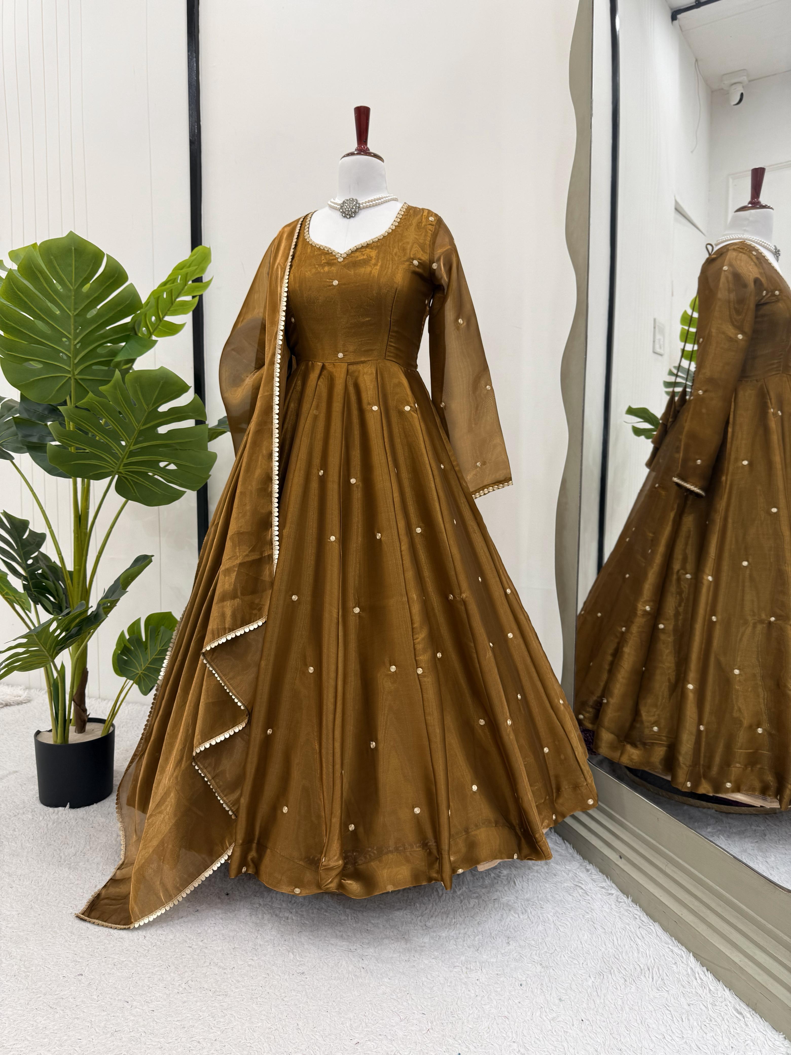 Brown evening Anarkali gown or dress with sheer overlay on a mannequin against a white wall.