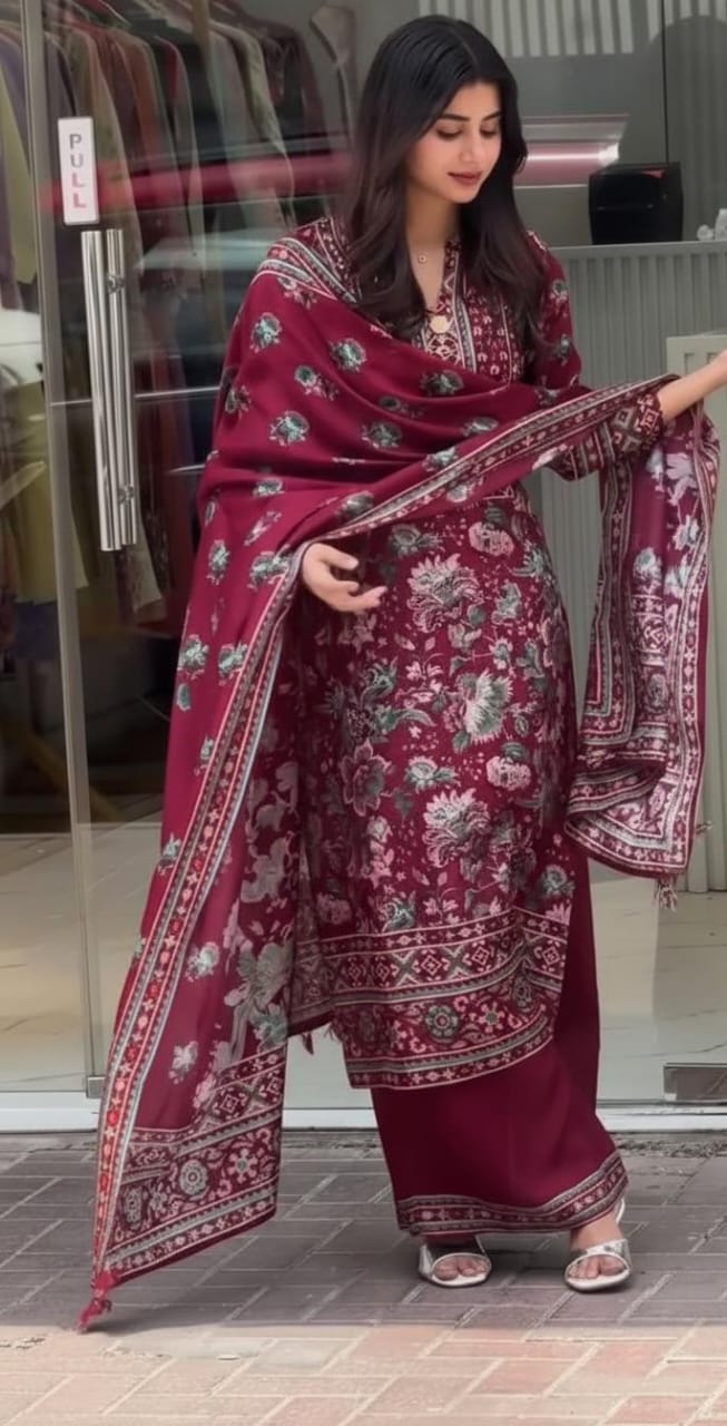 A woman holding a maroon floral dupatta in front of a store entrance.