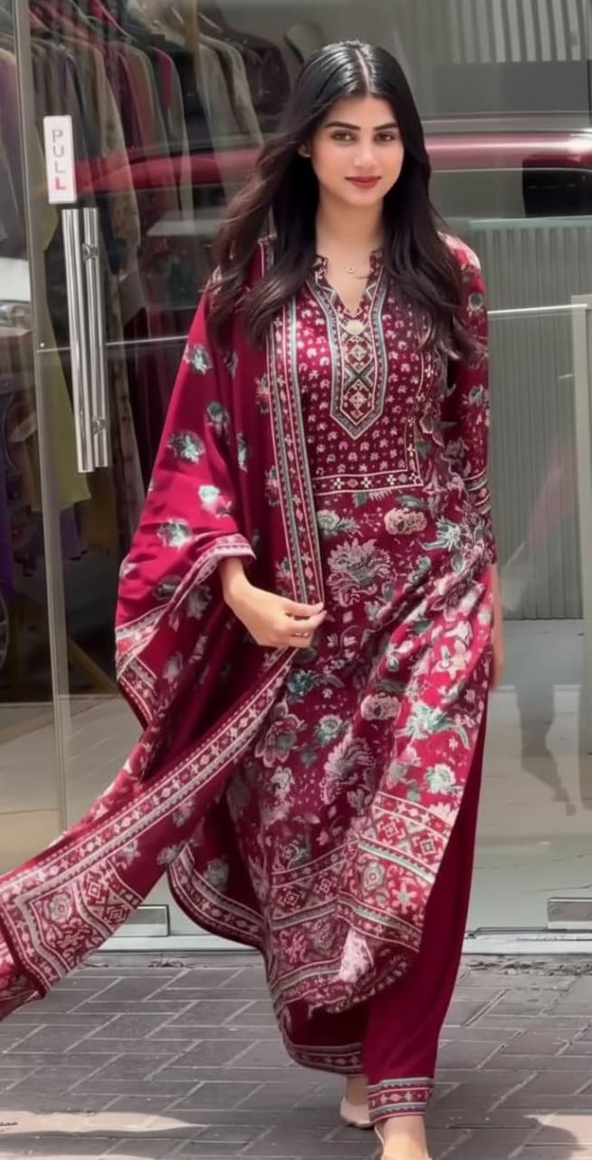 A woman wearing a maroon kurta set dress paired with a matching dupatta, set against an urban backdrop.