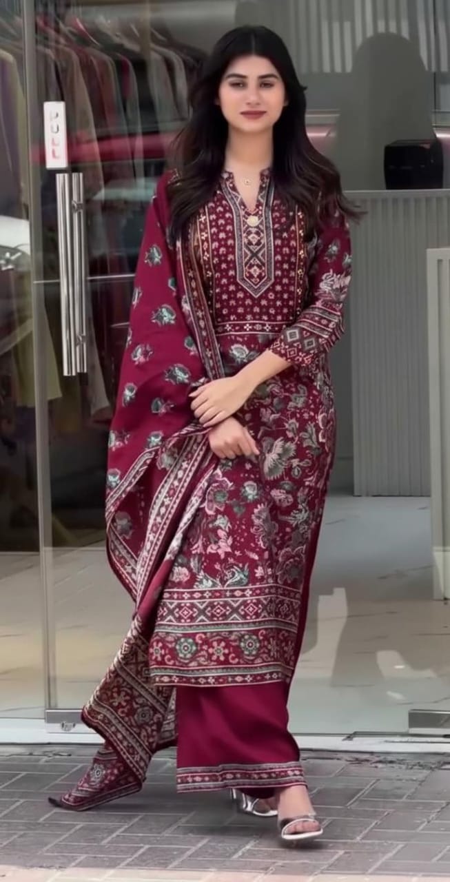 A woman wearing a maroon kurta set dress outfit with floral patterns in an indoor setting.