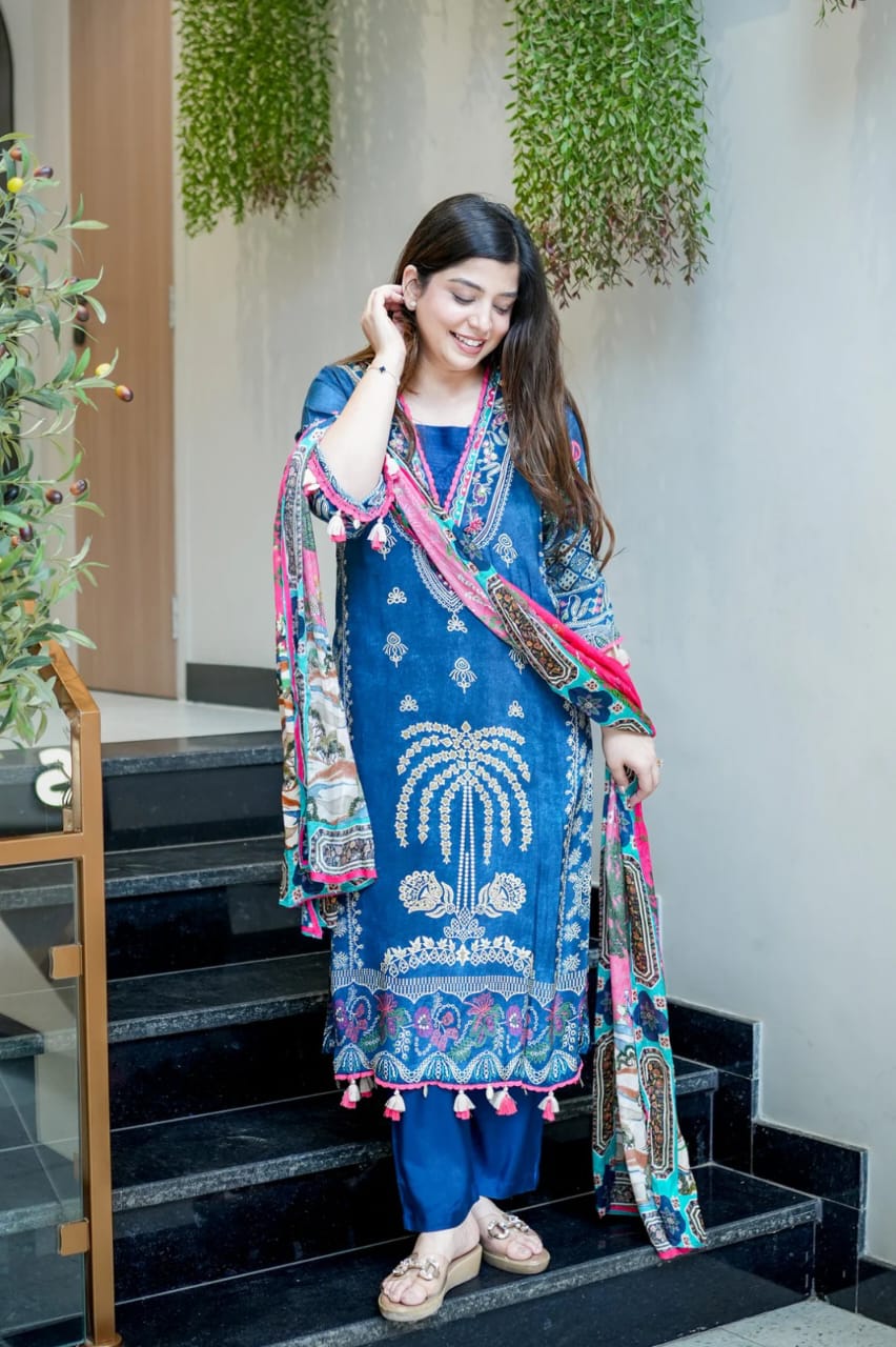 A woman wearing a blue digital-printed outfit paired with a colorful scarf, standing on a staircase.