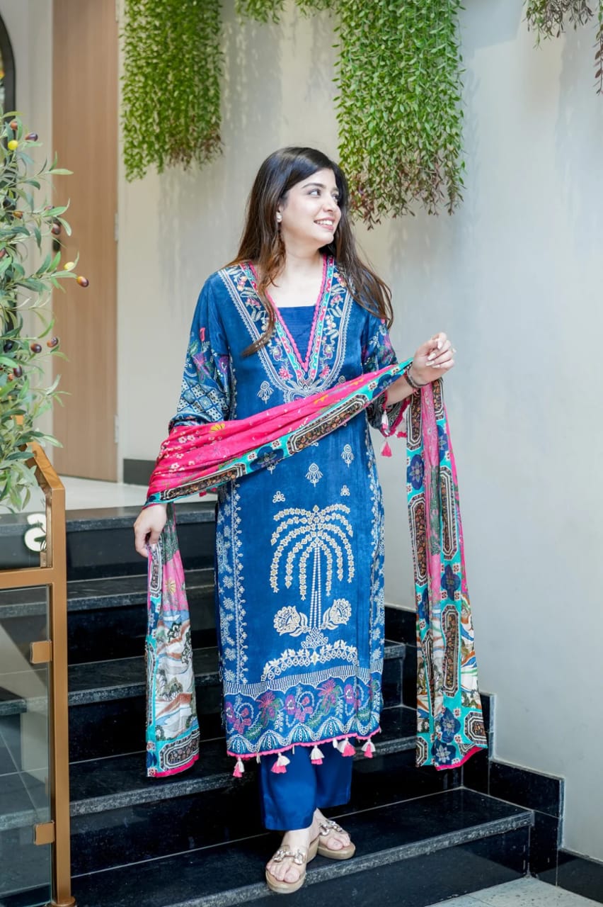 A woman wearing a blue digital-printed outfit paired with a pink dupatta, standing on a staircase.