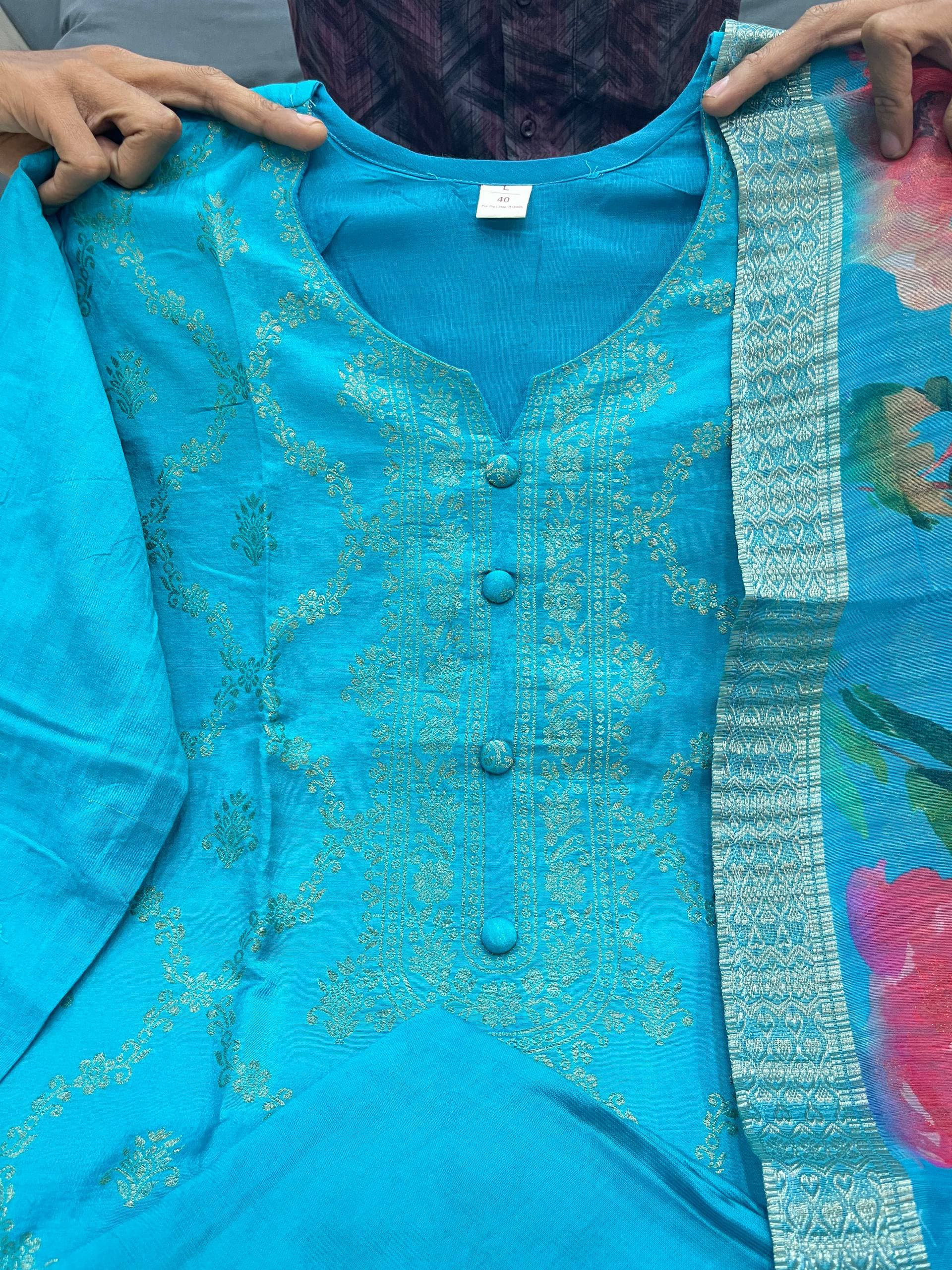 Blue kurta set with digital printed garment held by a person with a colorful background