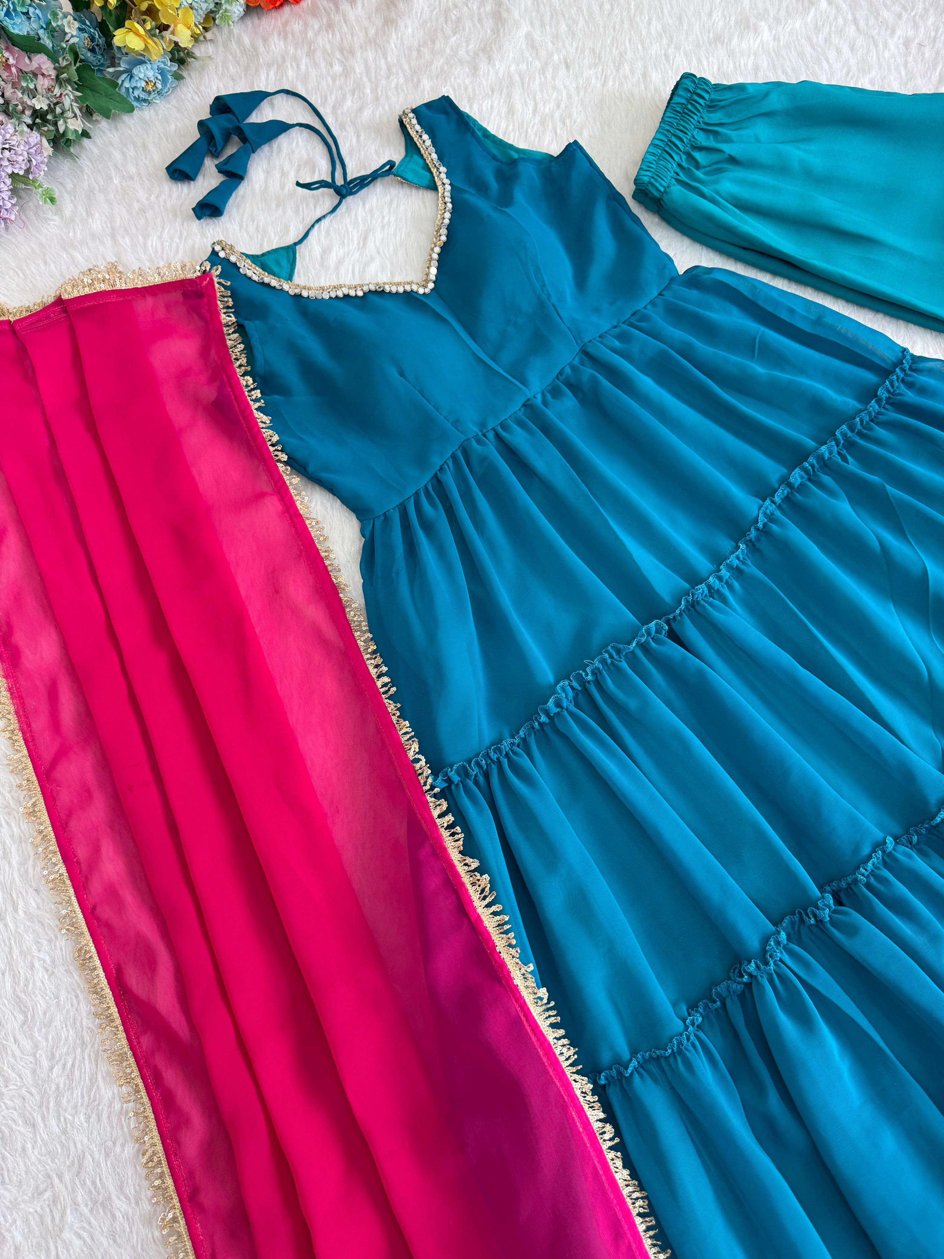 Blue anarkali dress with pink dupatta on a textured surface