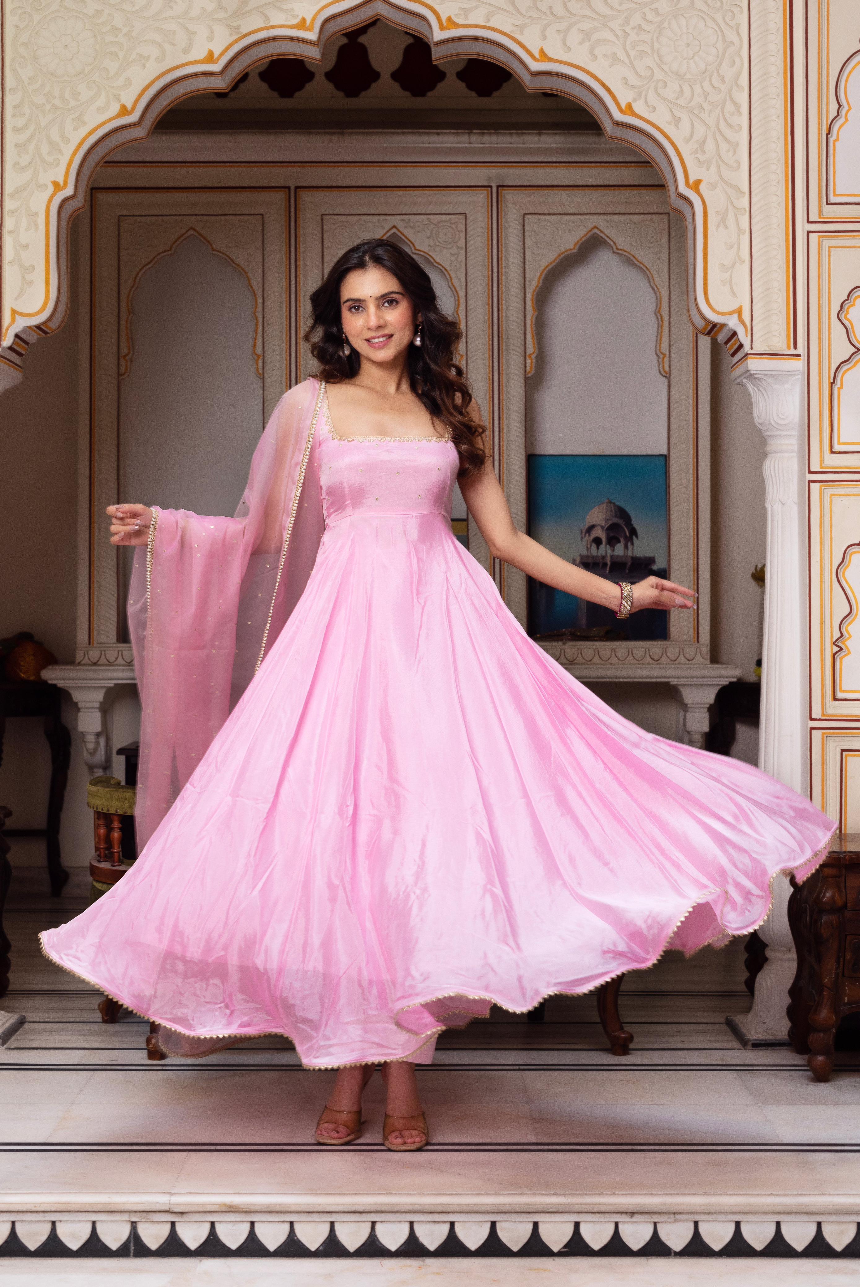Woman in a pink traditional outfit standing in an ornate room.