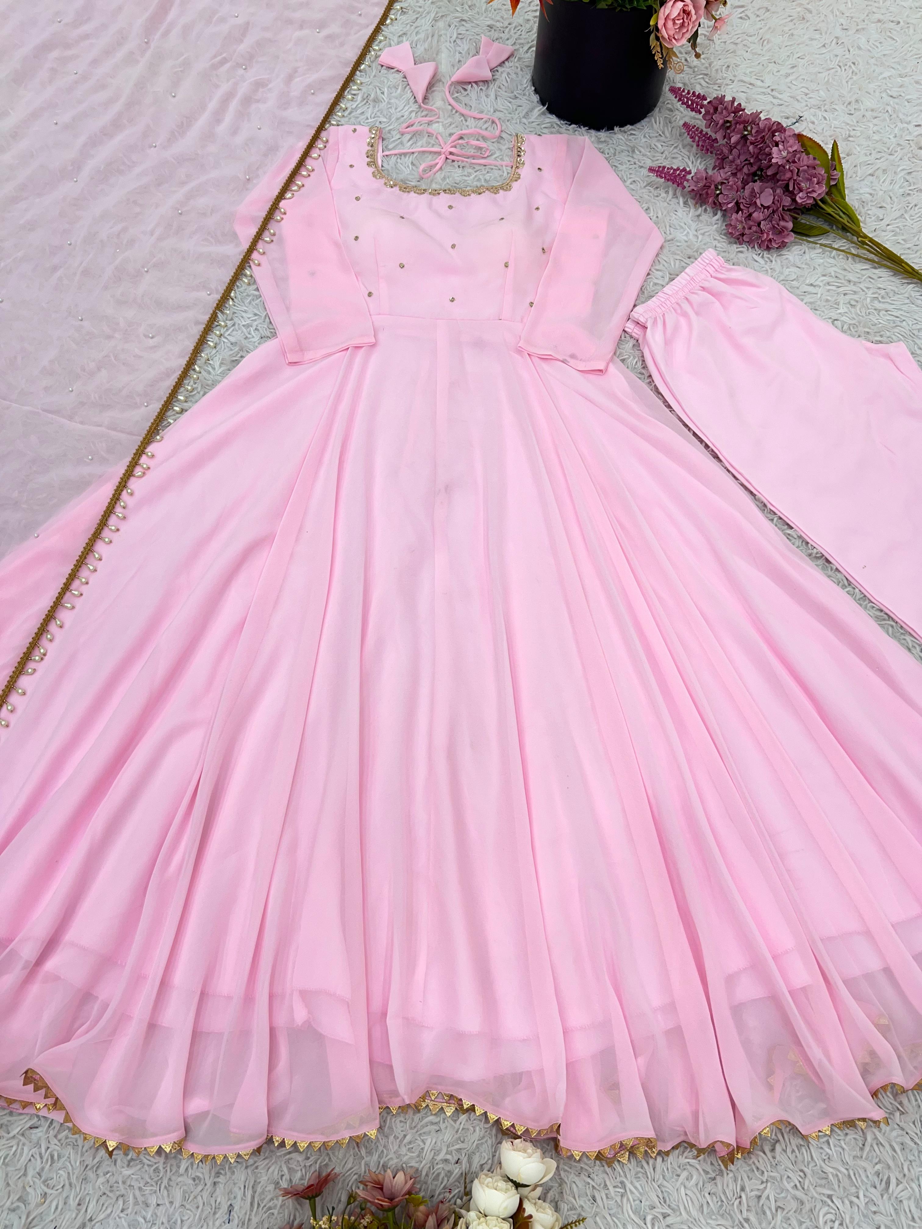 Pink dress with floral embellishments on a textured surface with flowers and butterflies.