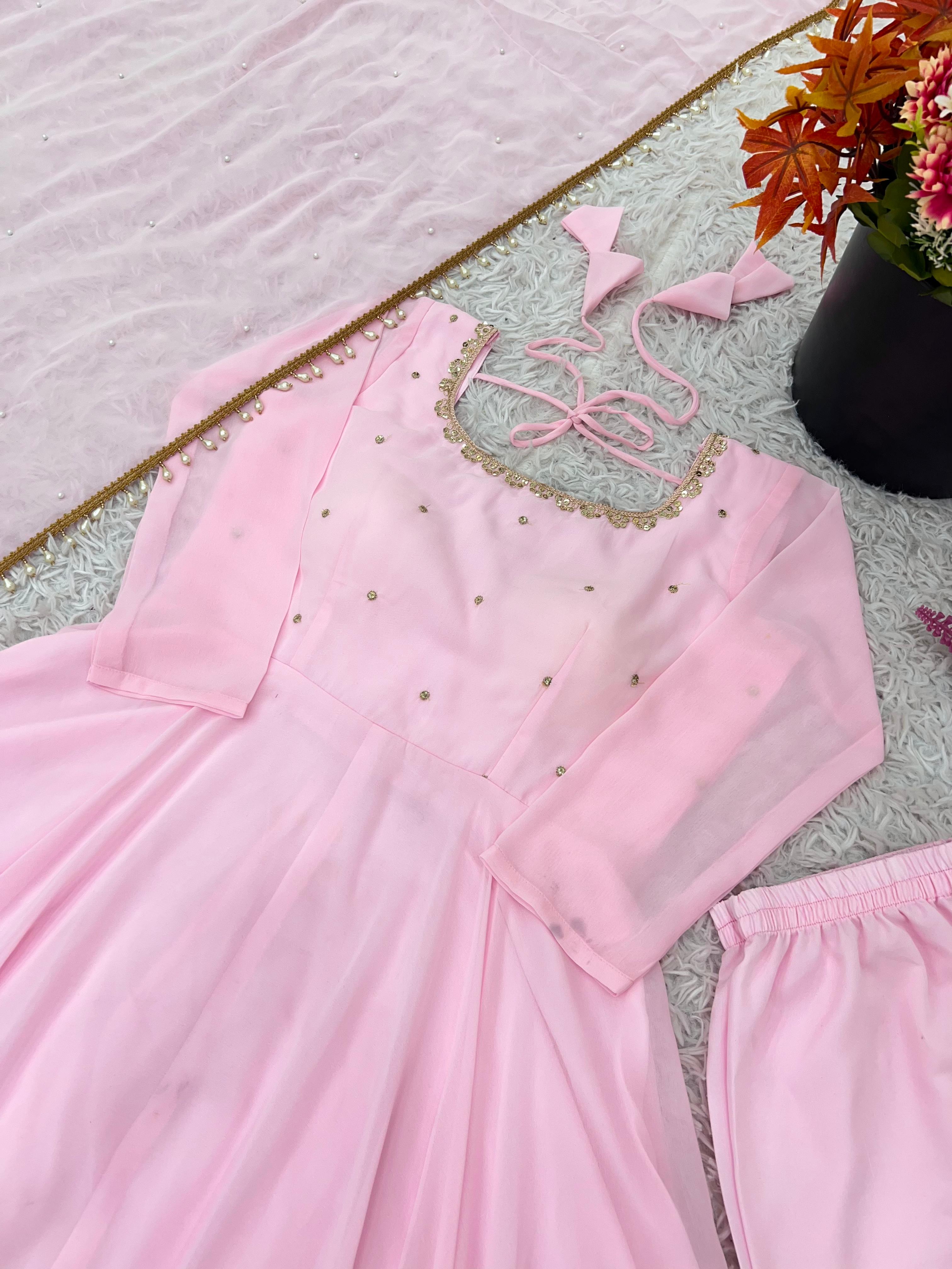Pink traditional outfit with matching dupatta on a textured surface.