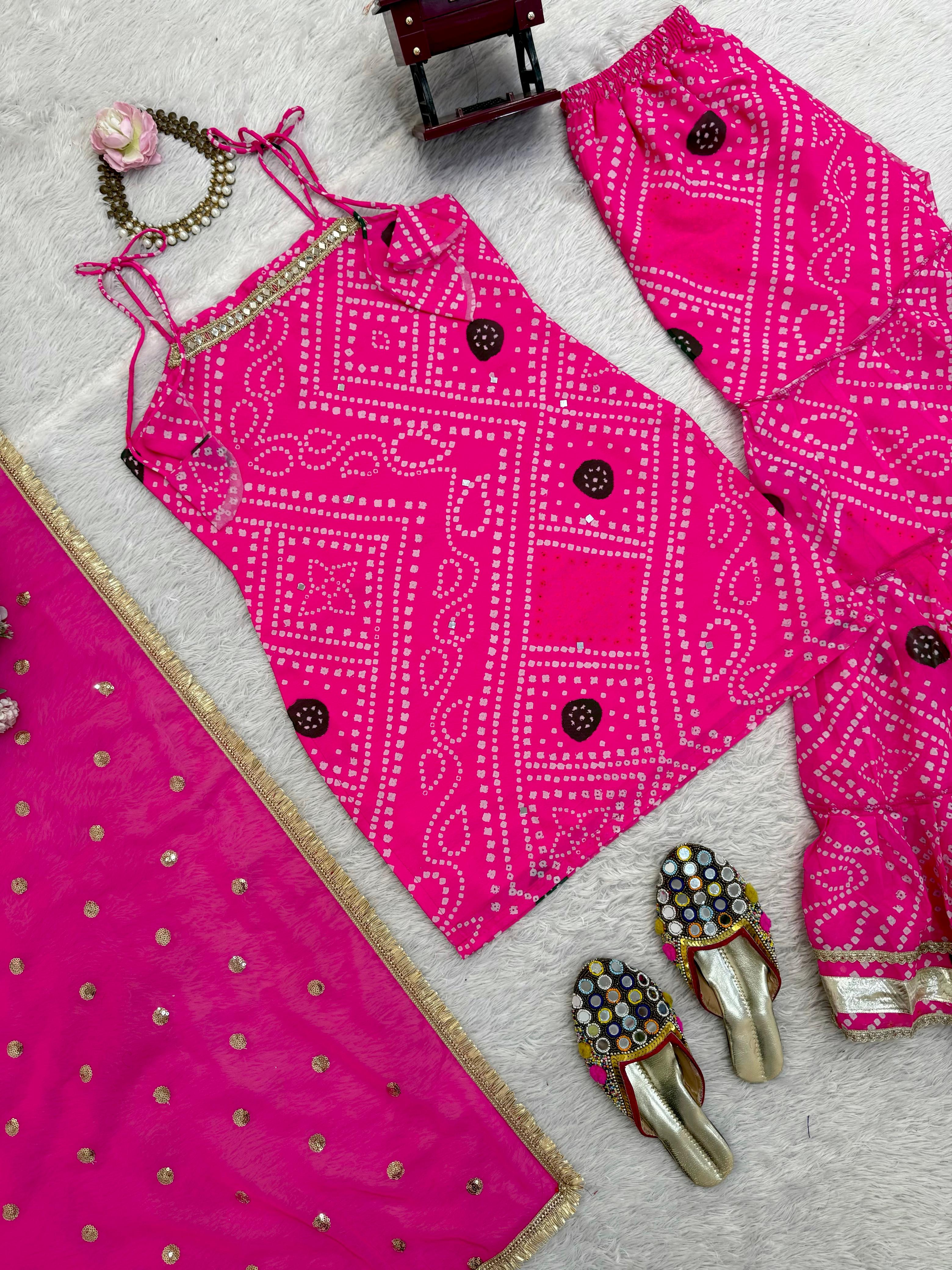 Pink sharara set outfit with matching shoes and jewelry on a light gray background