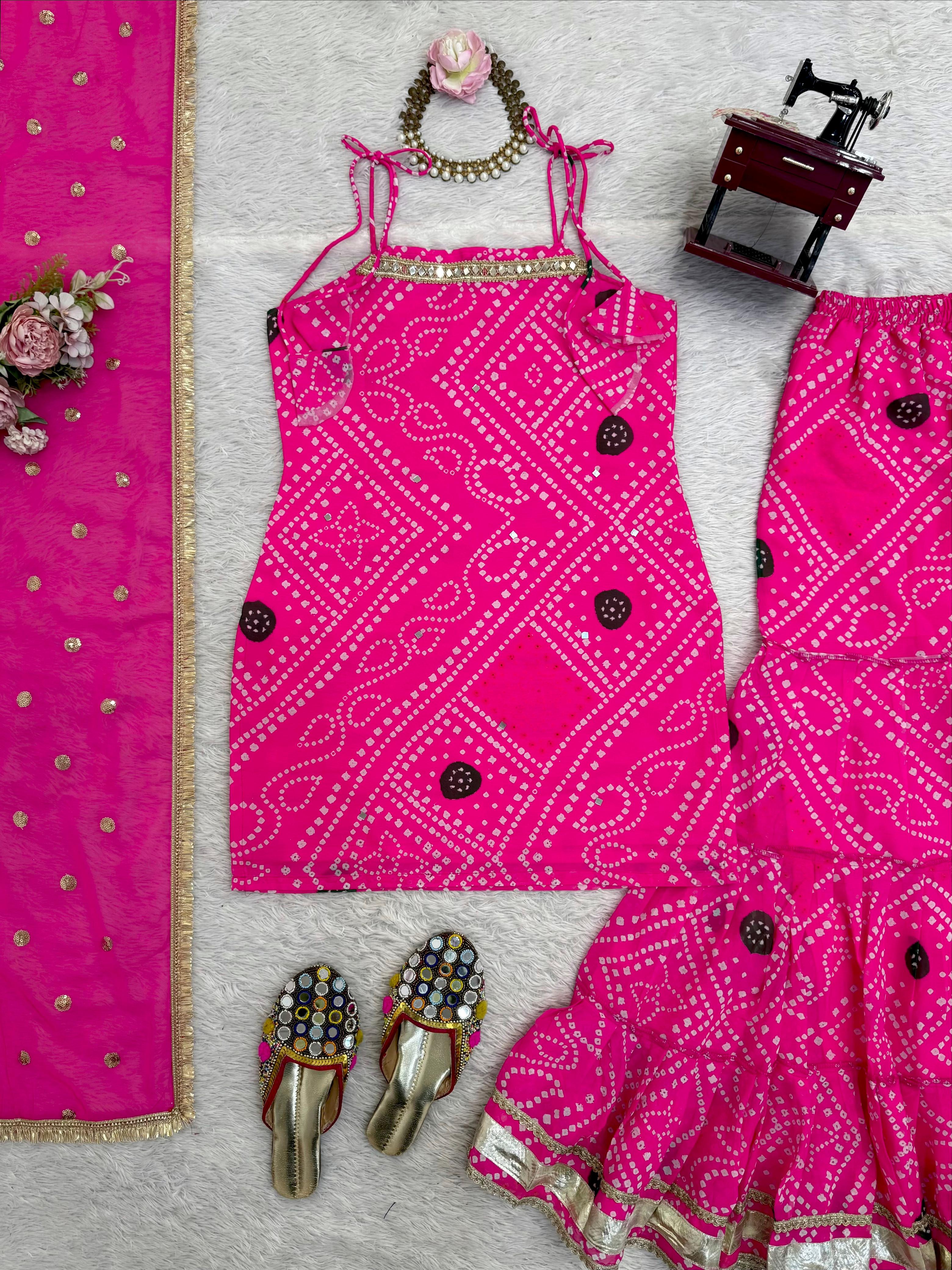 Pink sharara set outfit with matching dupatta, shoes, and jewelry on a light gray background