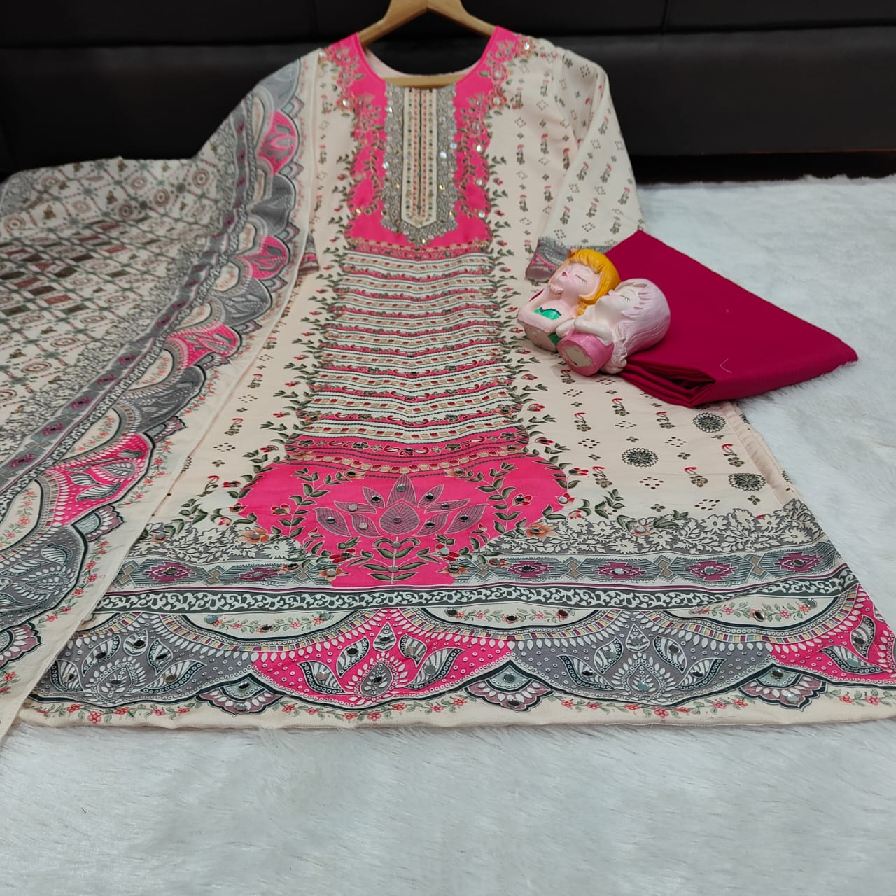 Embroidered fabric with pink and gray patterns on a white surface