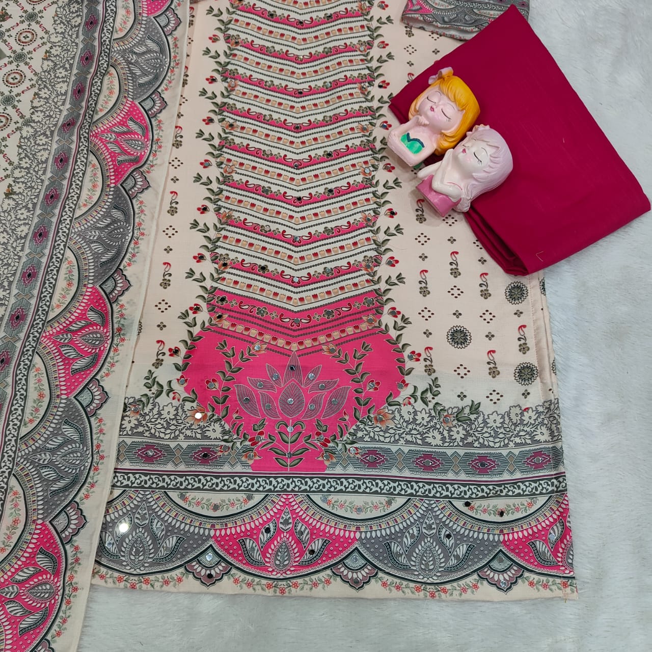 Decorative fabric with intricate patterns and a small plush toy on a light background