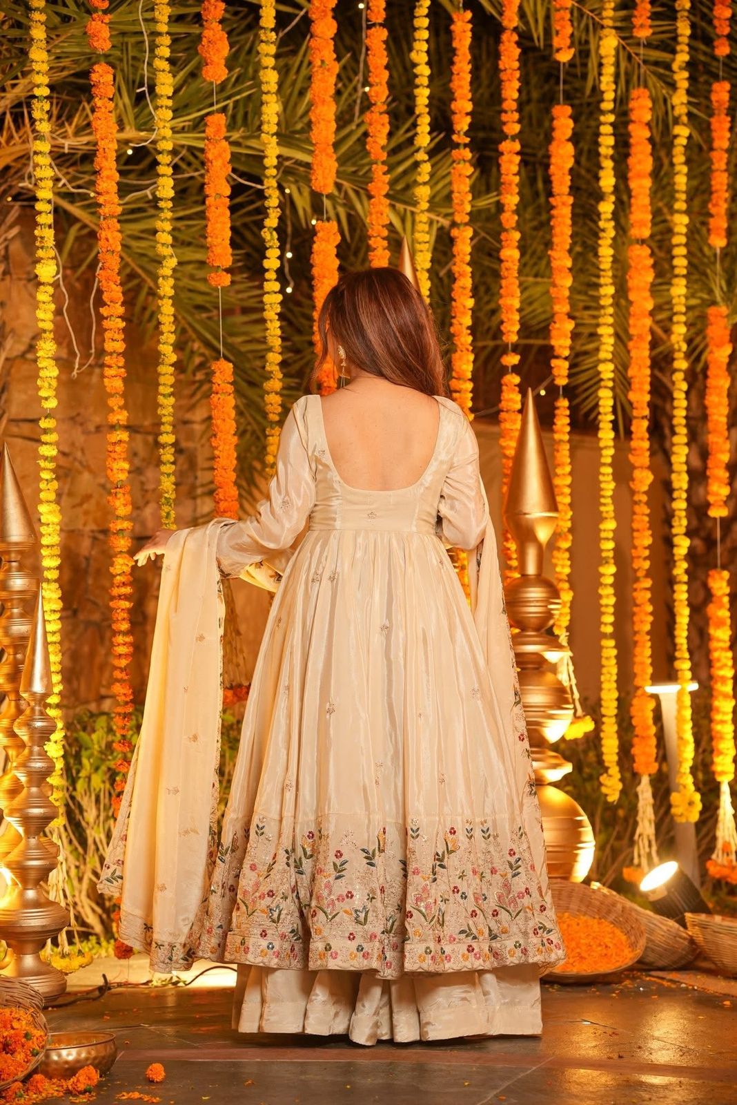 Woman in a traditional outfit standing in front of floral decorations