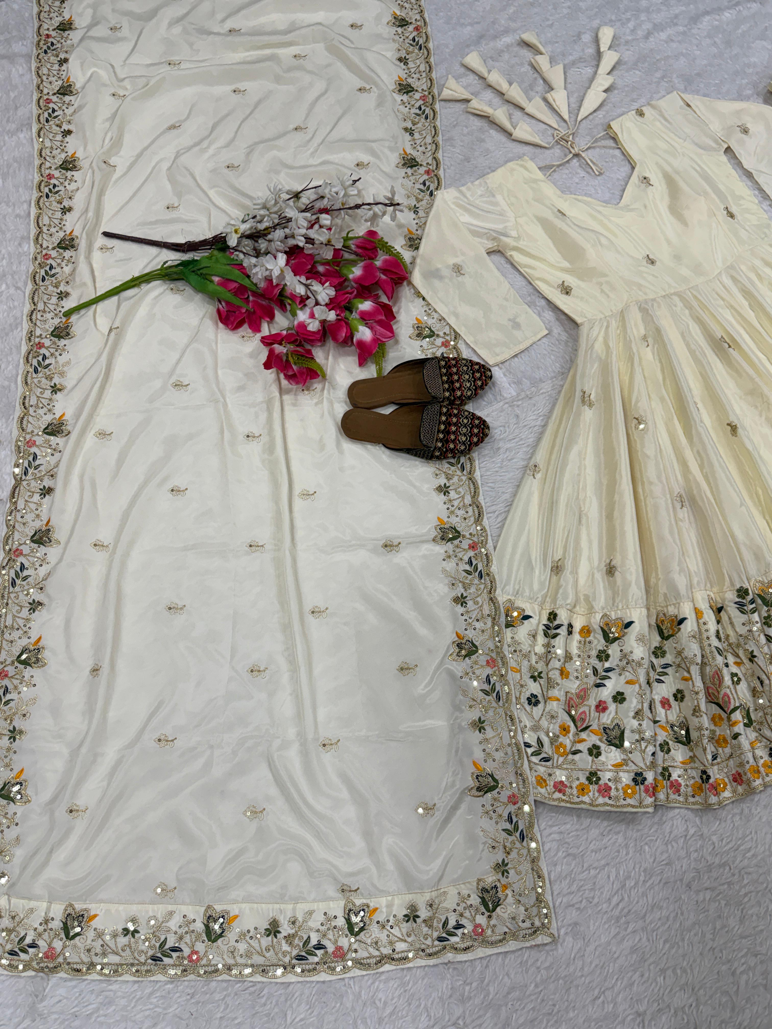 White embroidered saree with floral patterns on a textured surface