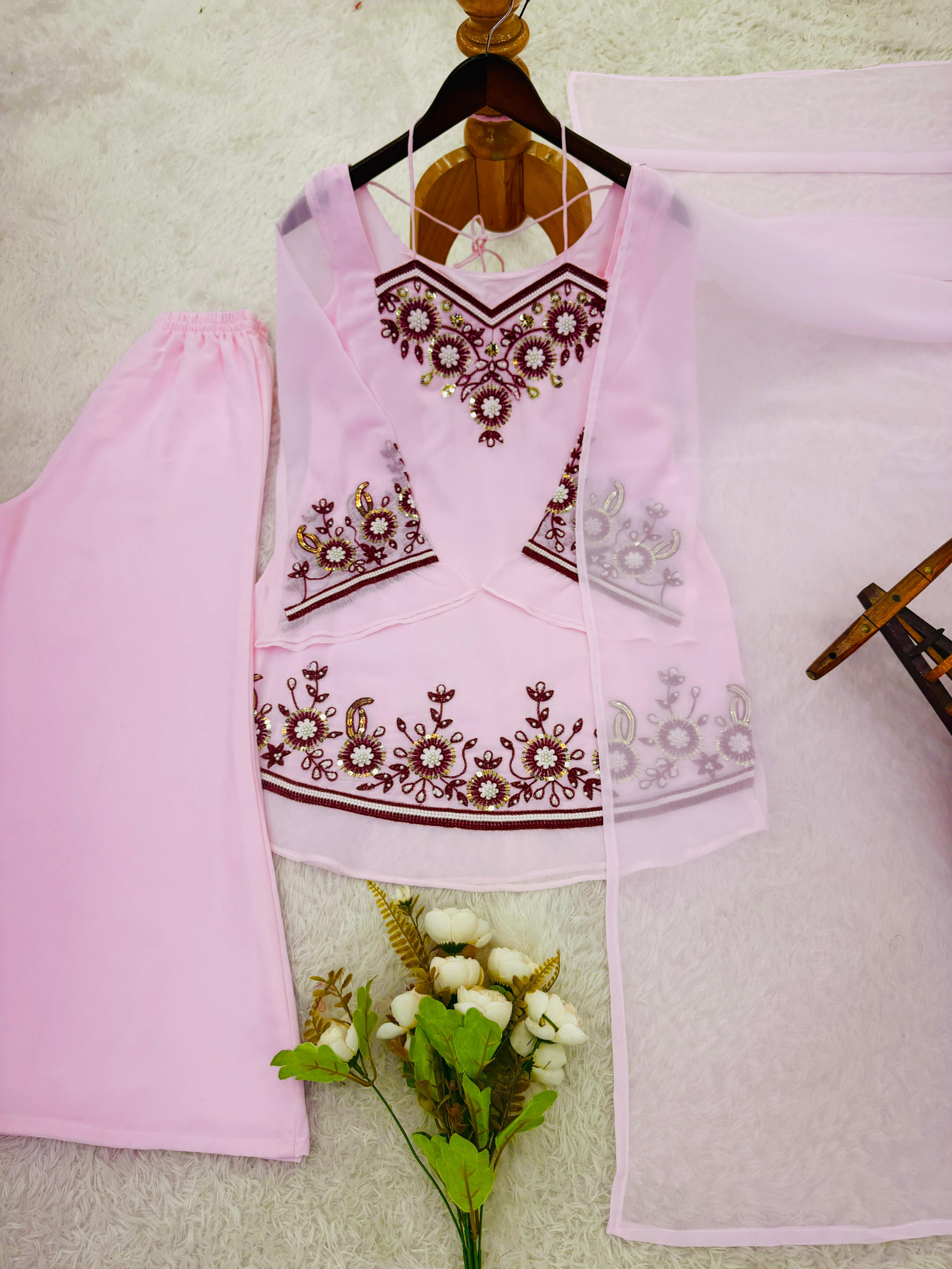 Pink embroidered traditional outfit on a hanger with a white background