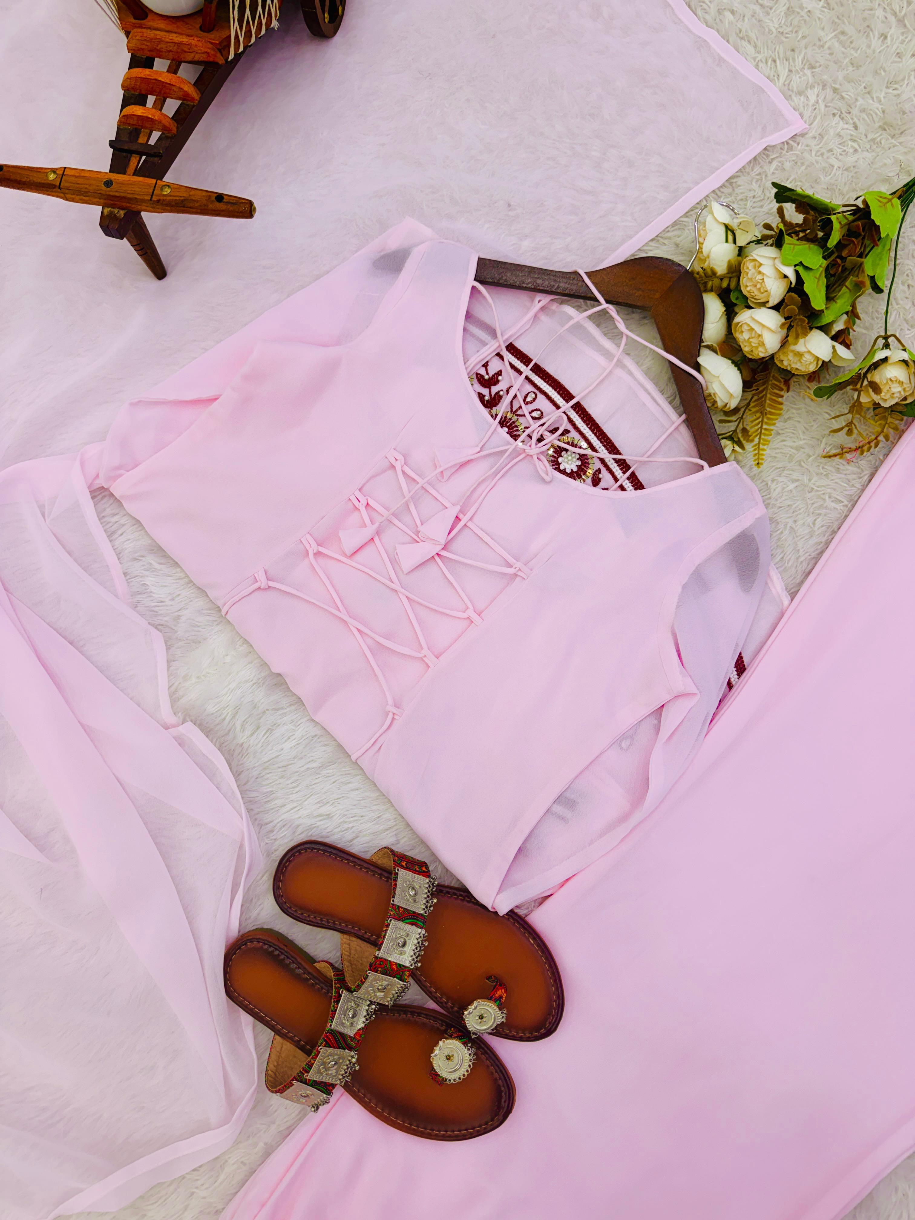 Pink traditional outfit with embroidered details on a light background