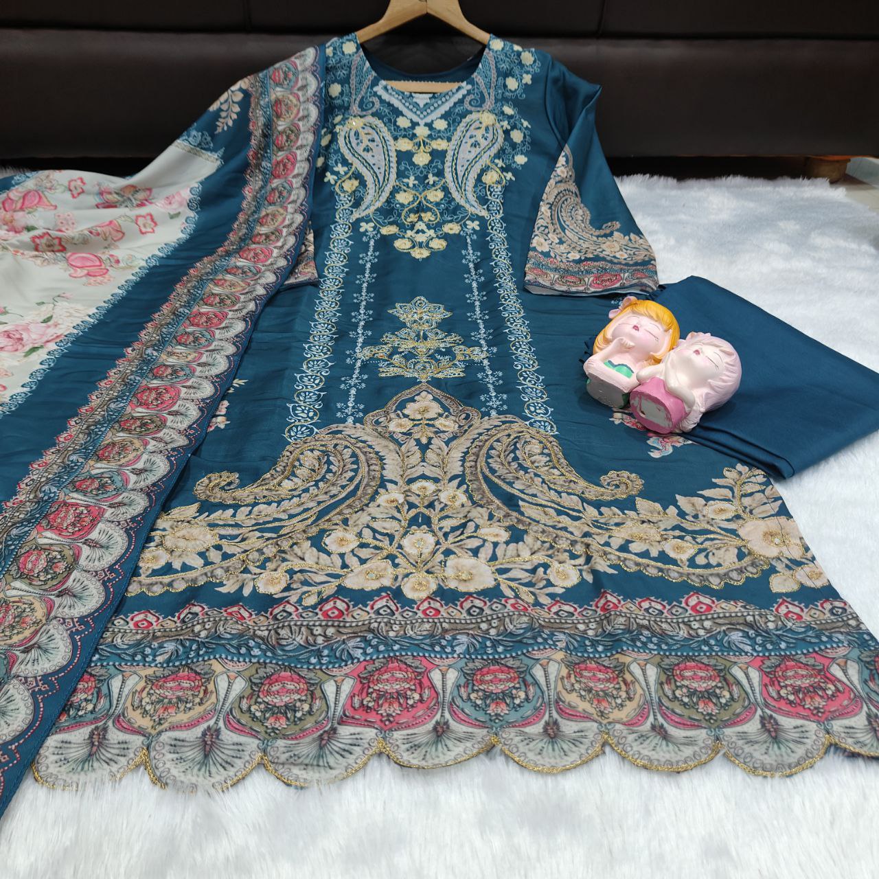 Blue embroidered fabric with intricate patterns on a white surface