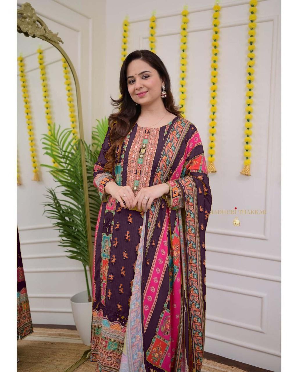 Woman wearing a colorful traditional outfit in a decorated room.