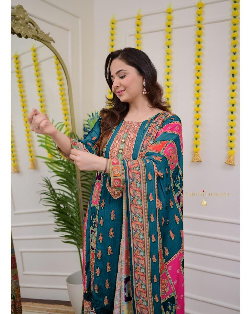 Woman in a colorful traditional outfit standing in a decorated room with yellow decorations on the wall.