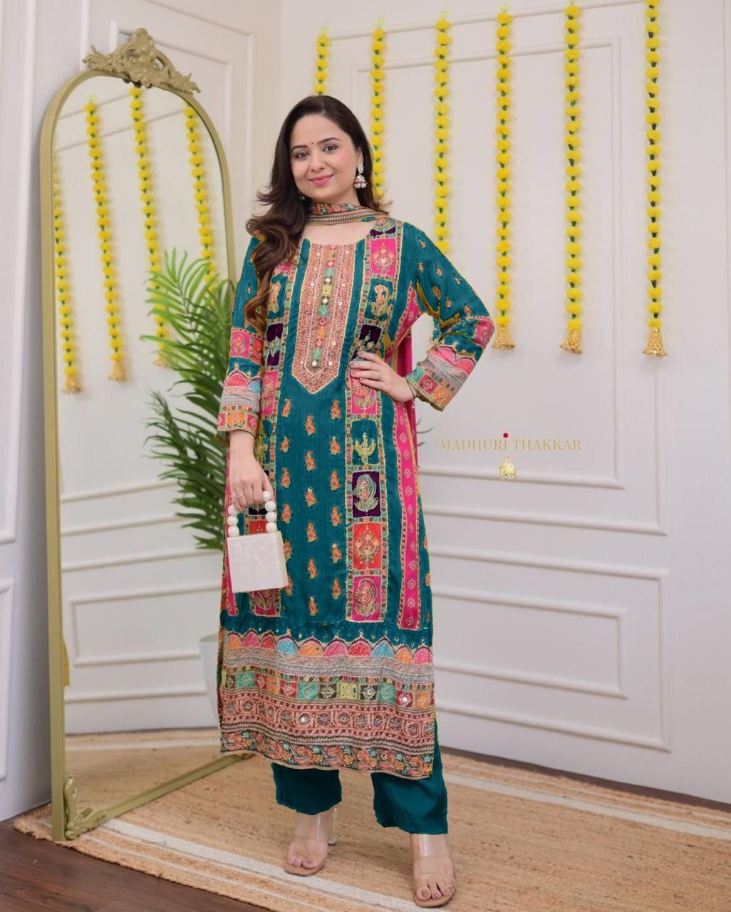 Woman in a colorful traditional outfit standing in front of a mirror with decorative elements.