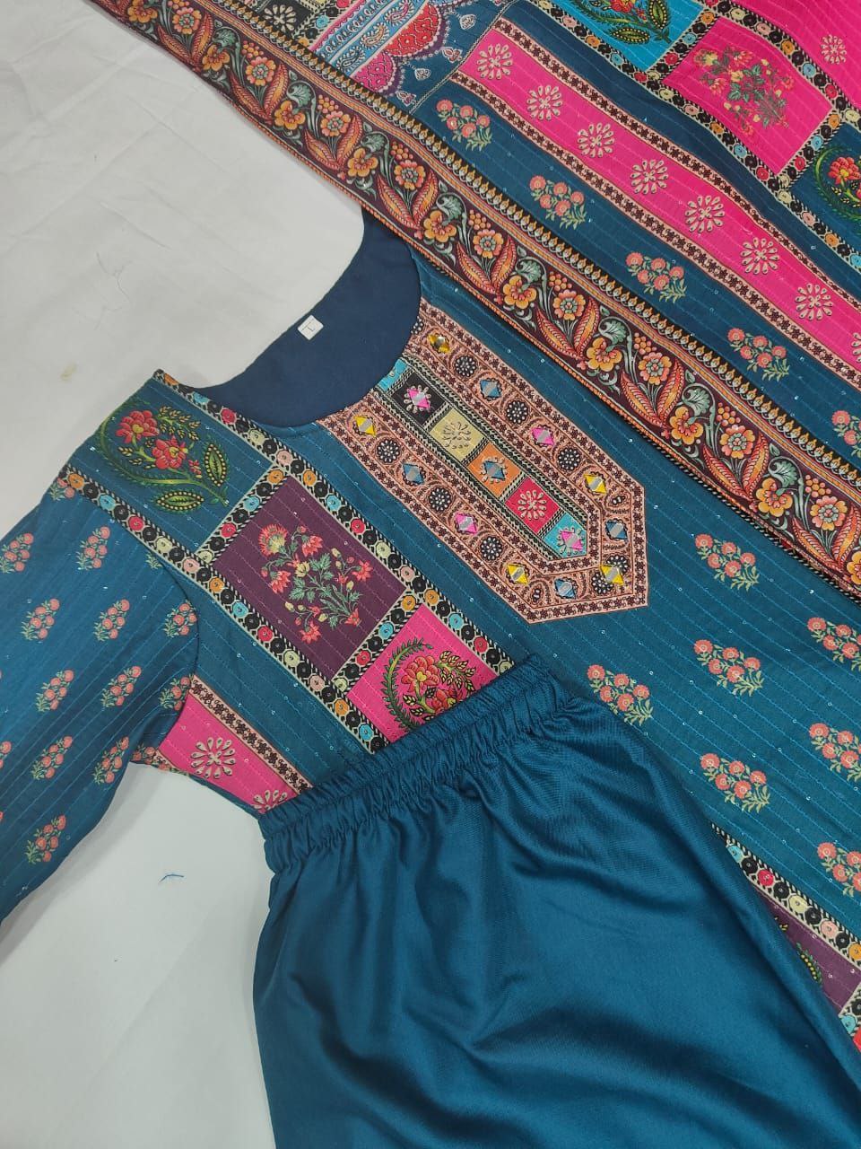 Traditional embroidered garment on a mannequin with colorful patterns.